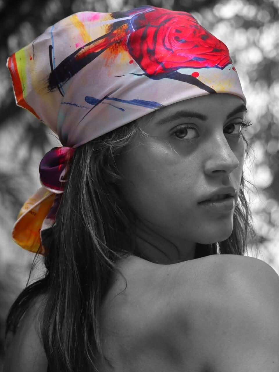 Model wearing a Cult Luxury silk scarf with a colourful rose design, with her face and the background in black and white.