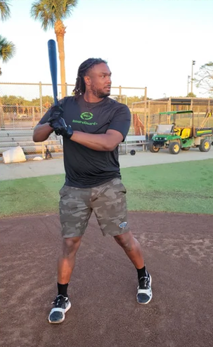 A person stands ready to bat on a baseball field, wearing athletic gear