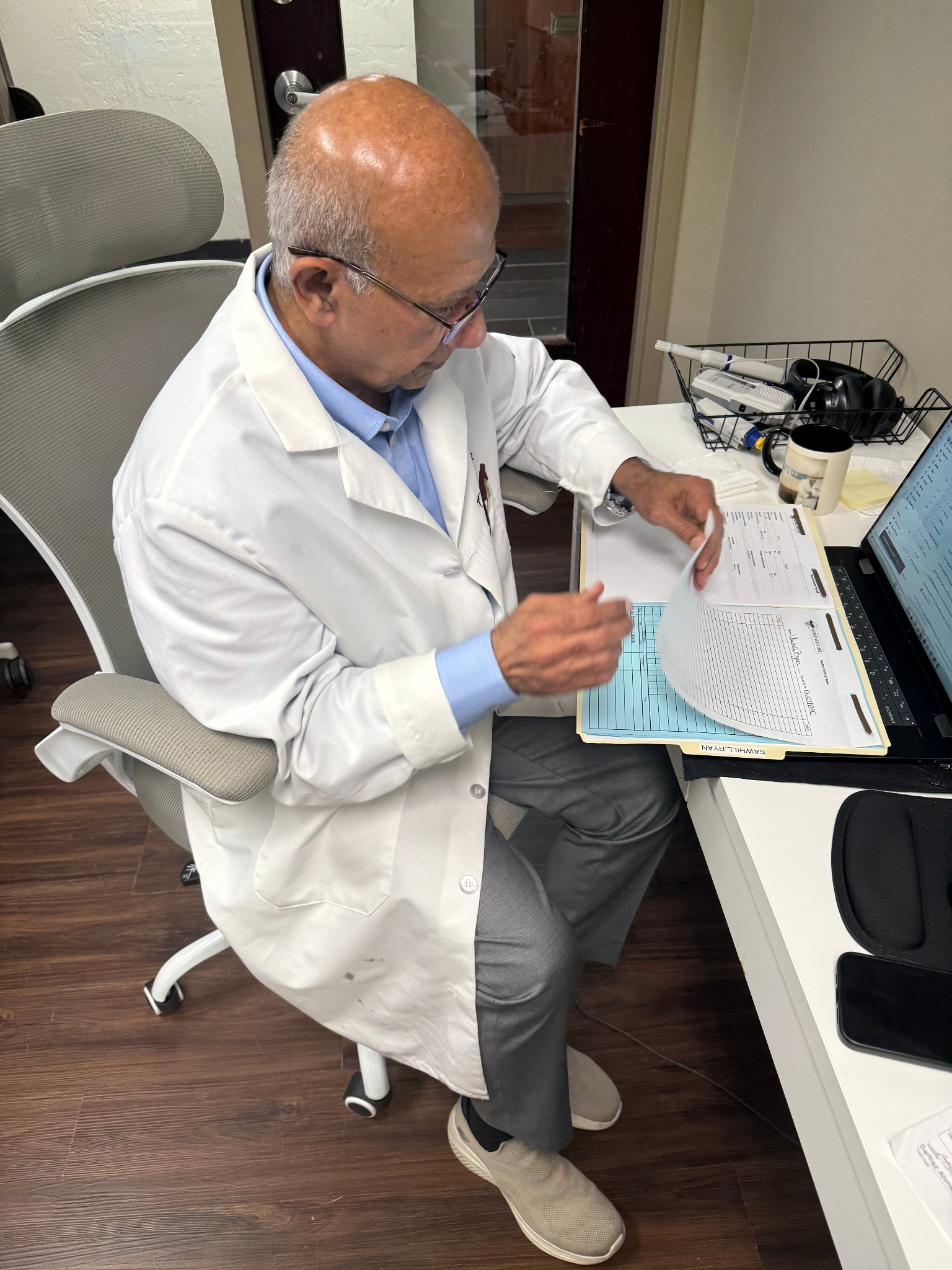 Doctor reviewing patient records at a desk inside Ultimate Men's Clinic.