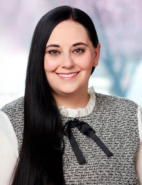 Portrait of a woman with long dark hair in a patterned blouse with a bow