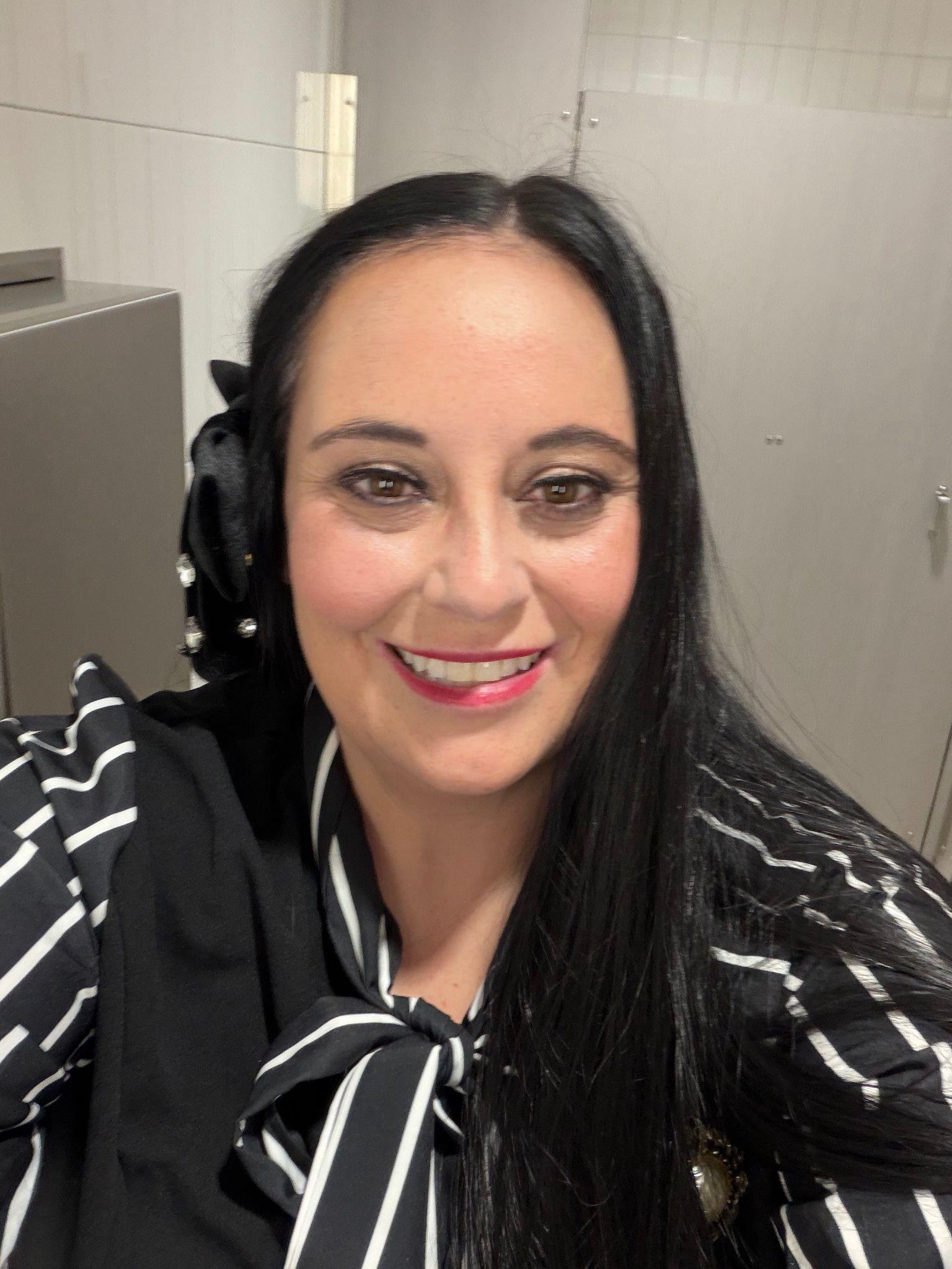 Smiling woman with long dark hair wearing a black and white striped top