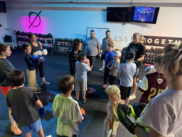 Group of adults and children participating in a boxing class at a gym