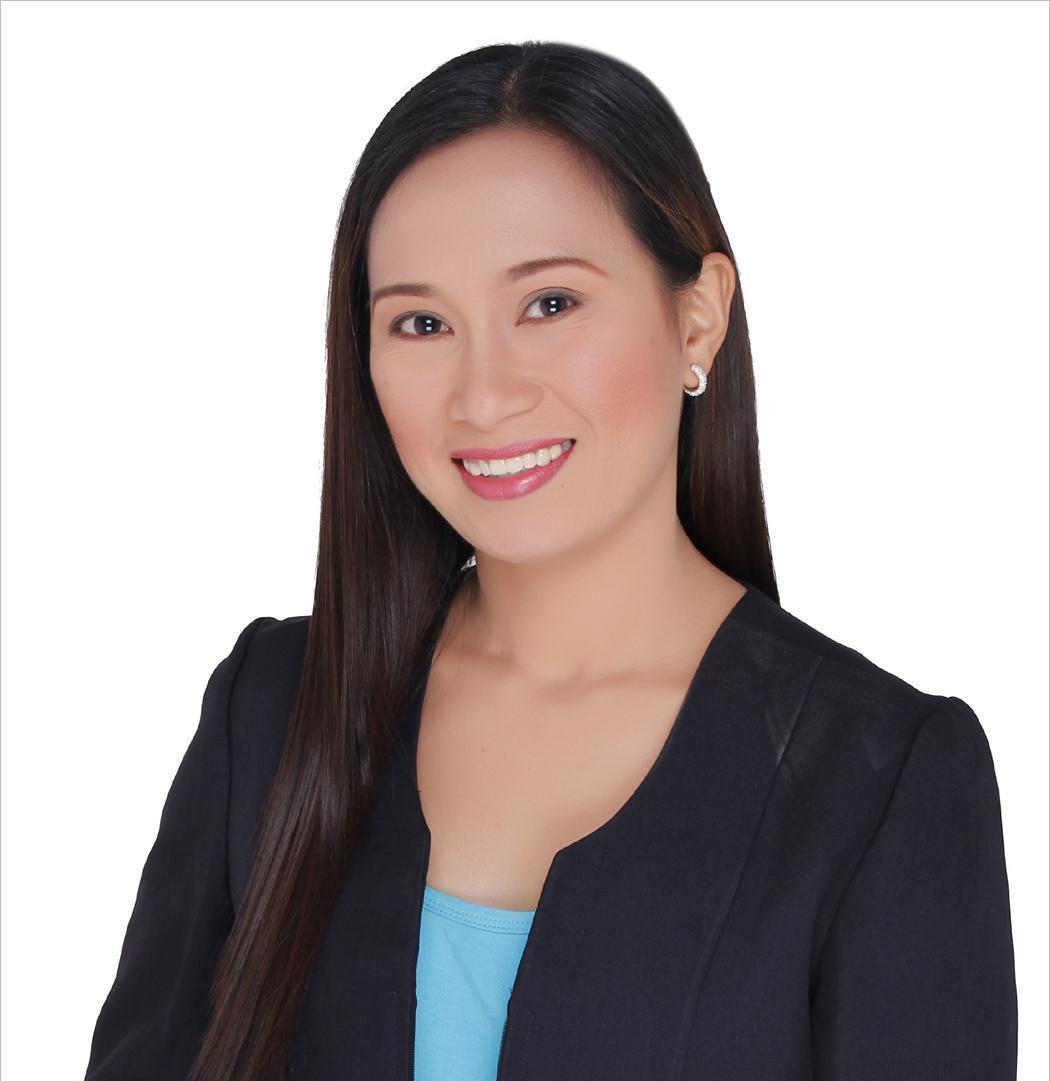Smiling woman in a black blazer with long, straight hair and a blue shirt