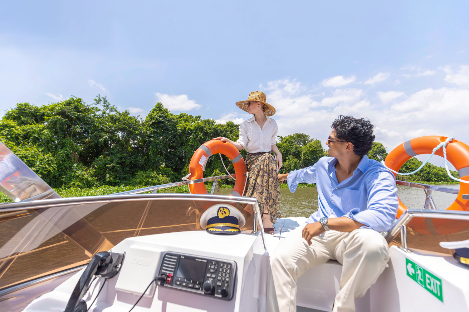 Two people on a boat enjoying a sunny day surrounded by greenery