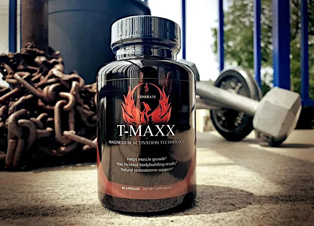 Black supplement bottle labeled T-MAXX with a weight and chains in the background