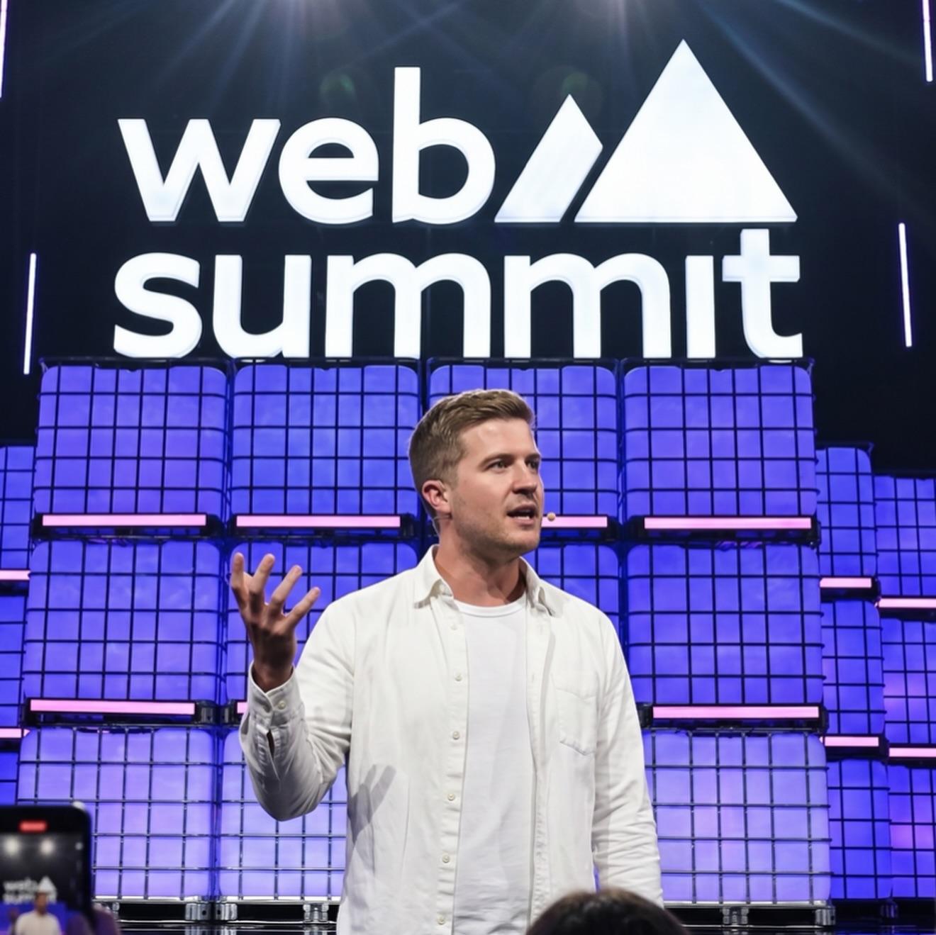 A speaker presenting at the Web Summit on a brightly lit stage