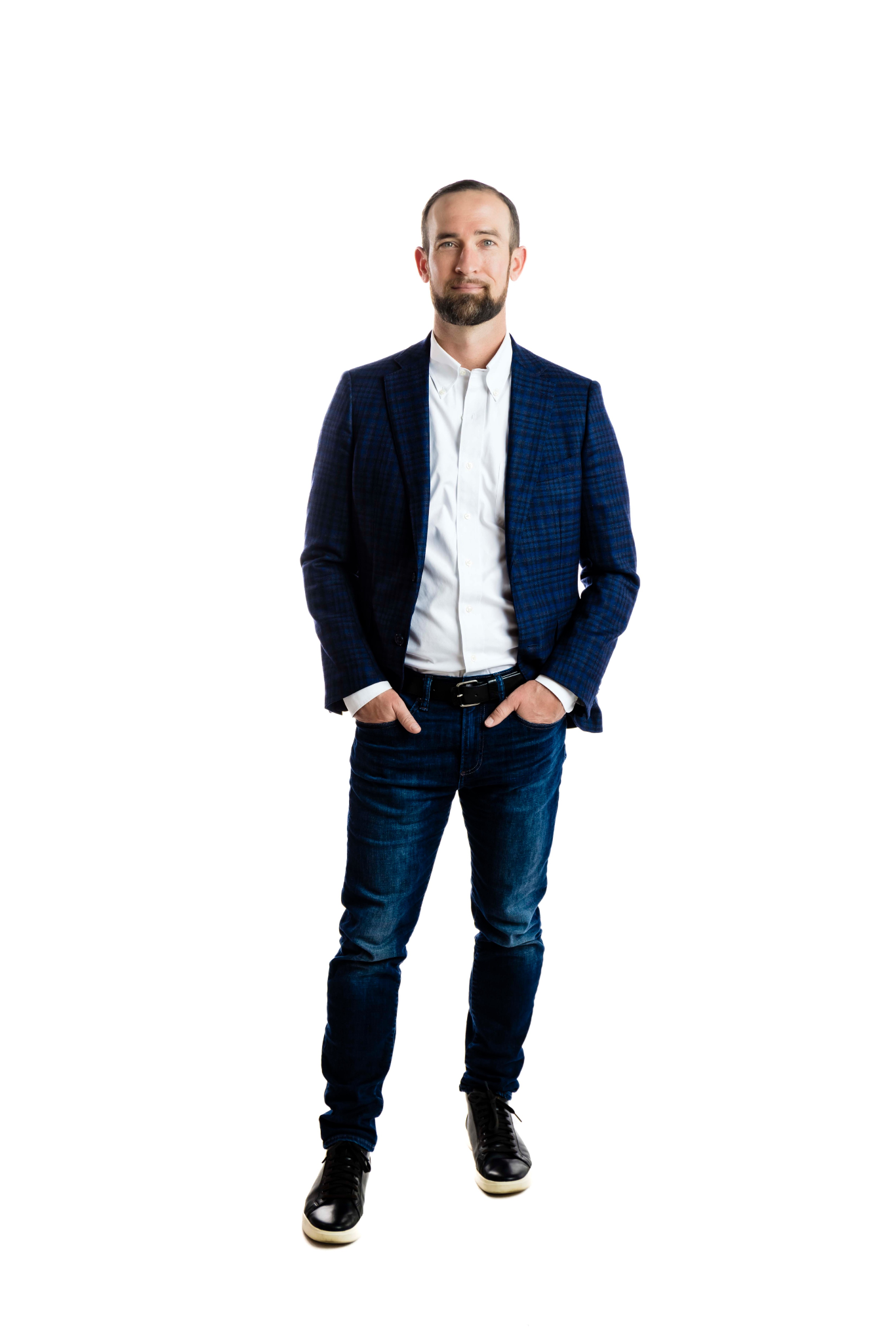 Man in a blue blazer and jeans standing confidently with hands in pockets