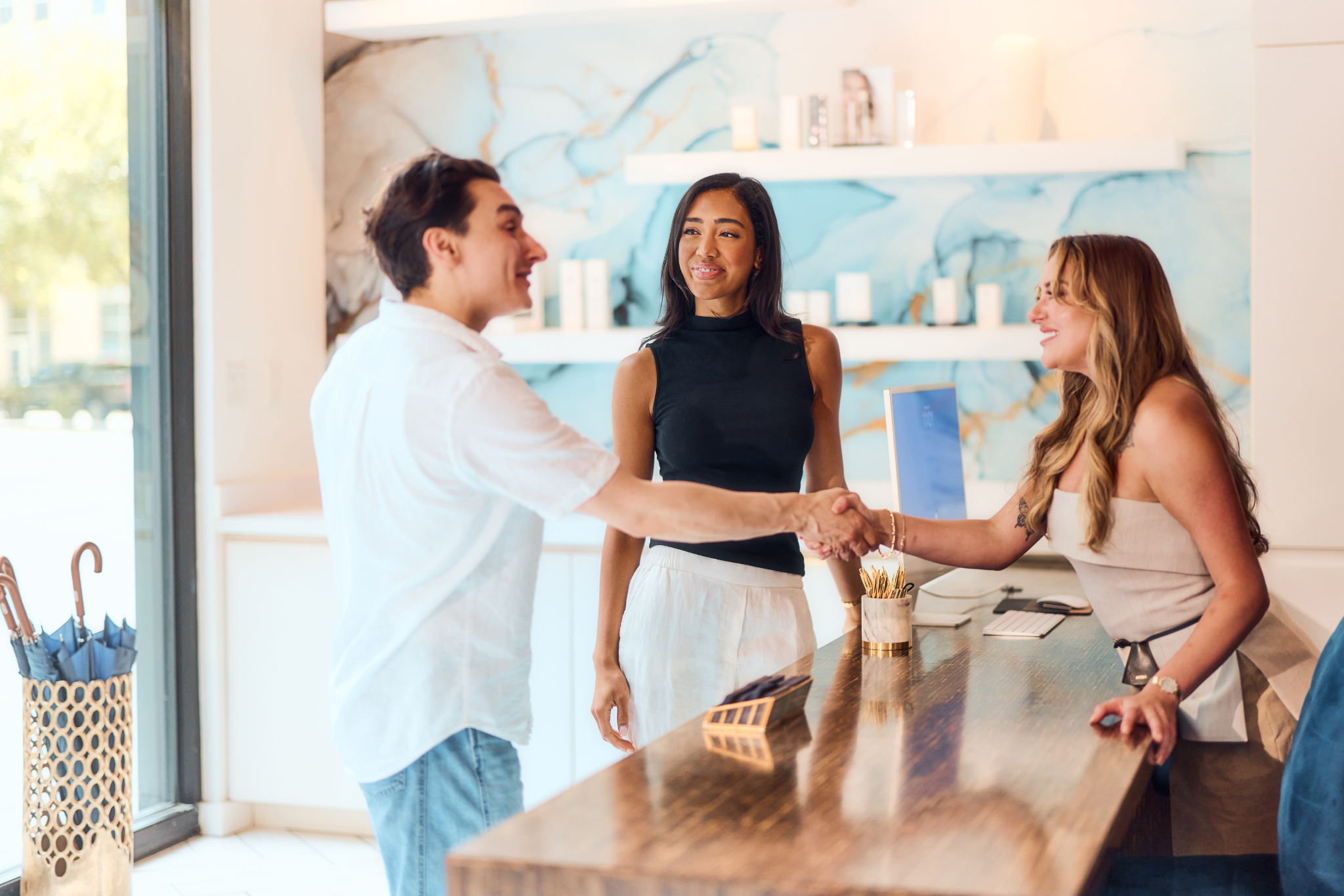 A man shakes hands with a woman at a stylish reception desk.