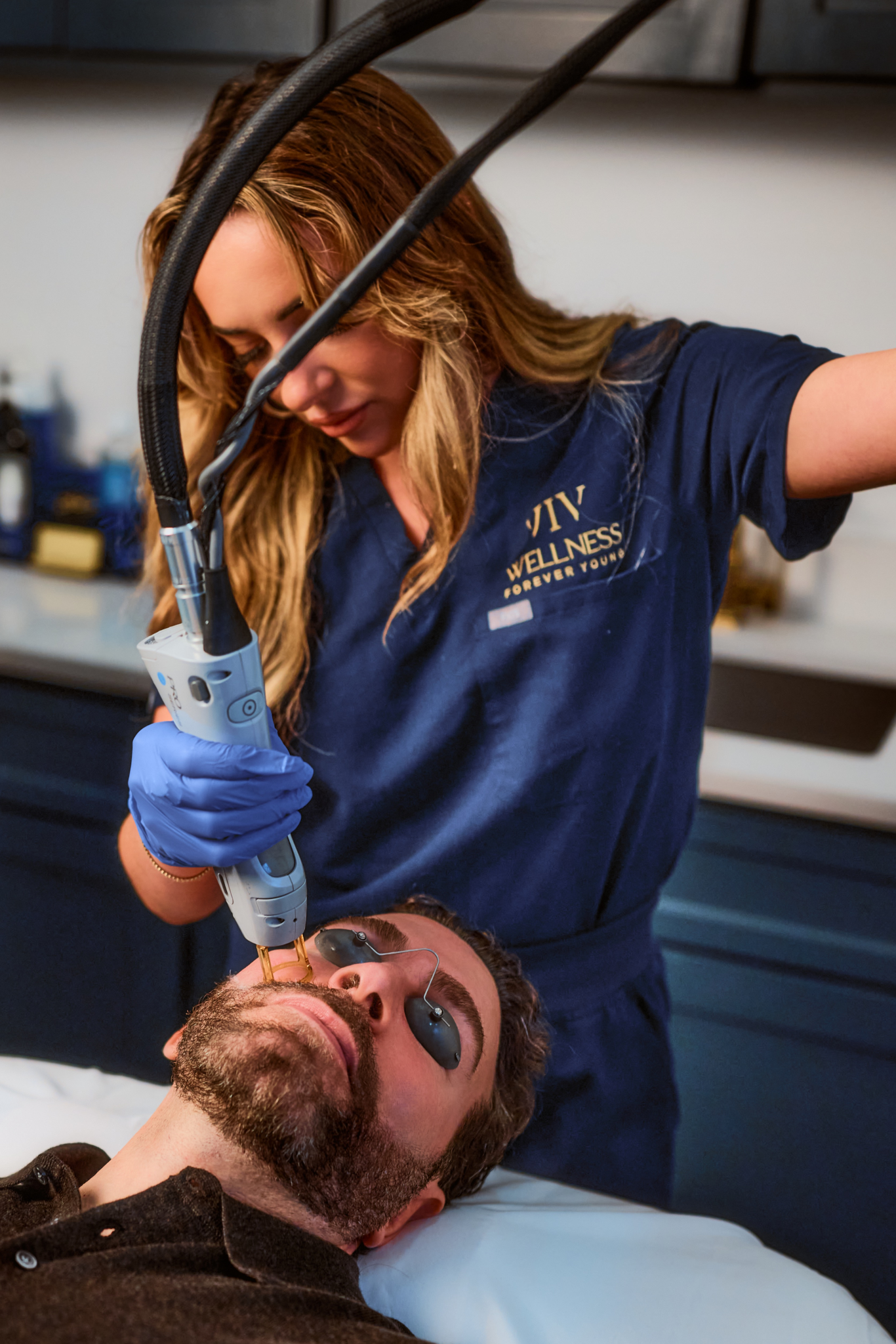 A skincare professional performs a laser treatment on a man's face in a clinic.