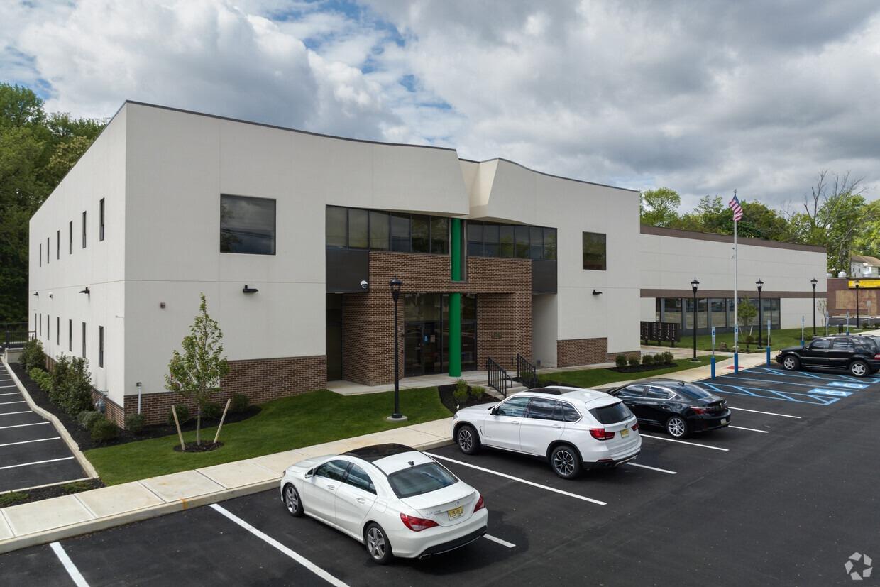 Modern two-story building with large windows and a landscaped parking lot