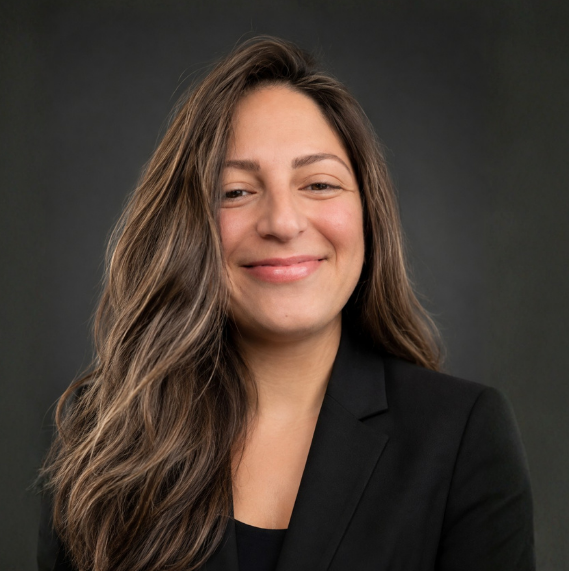 Smiling woman with long hair in a black blazer against a dark background