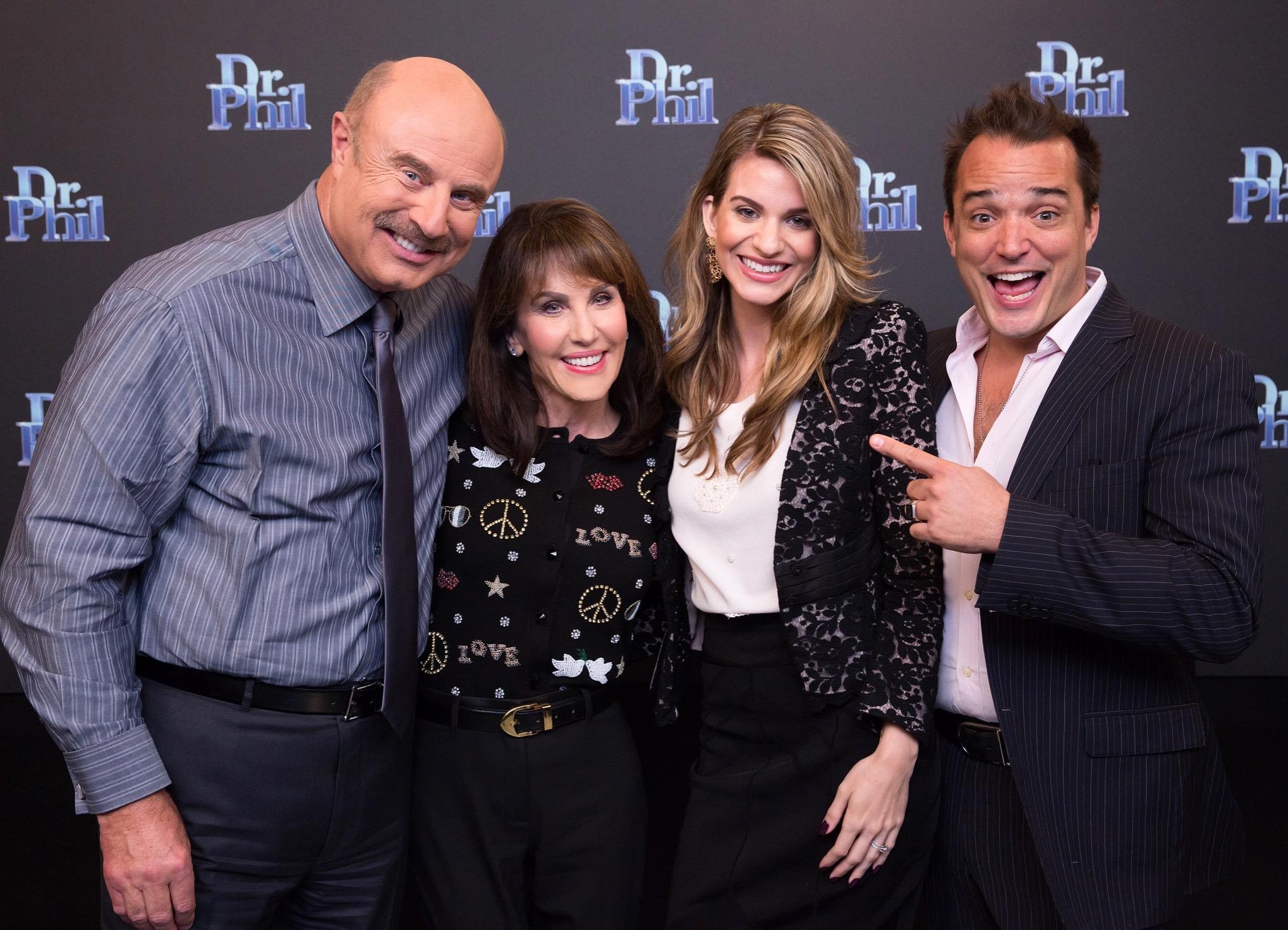 Four people smiling together at a promotional event for Dr. Phil's show