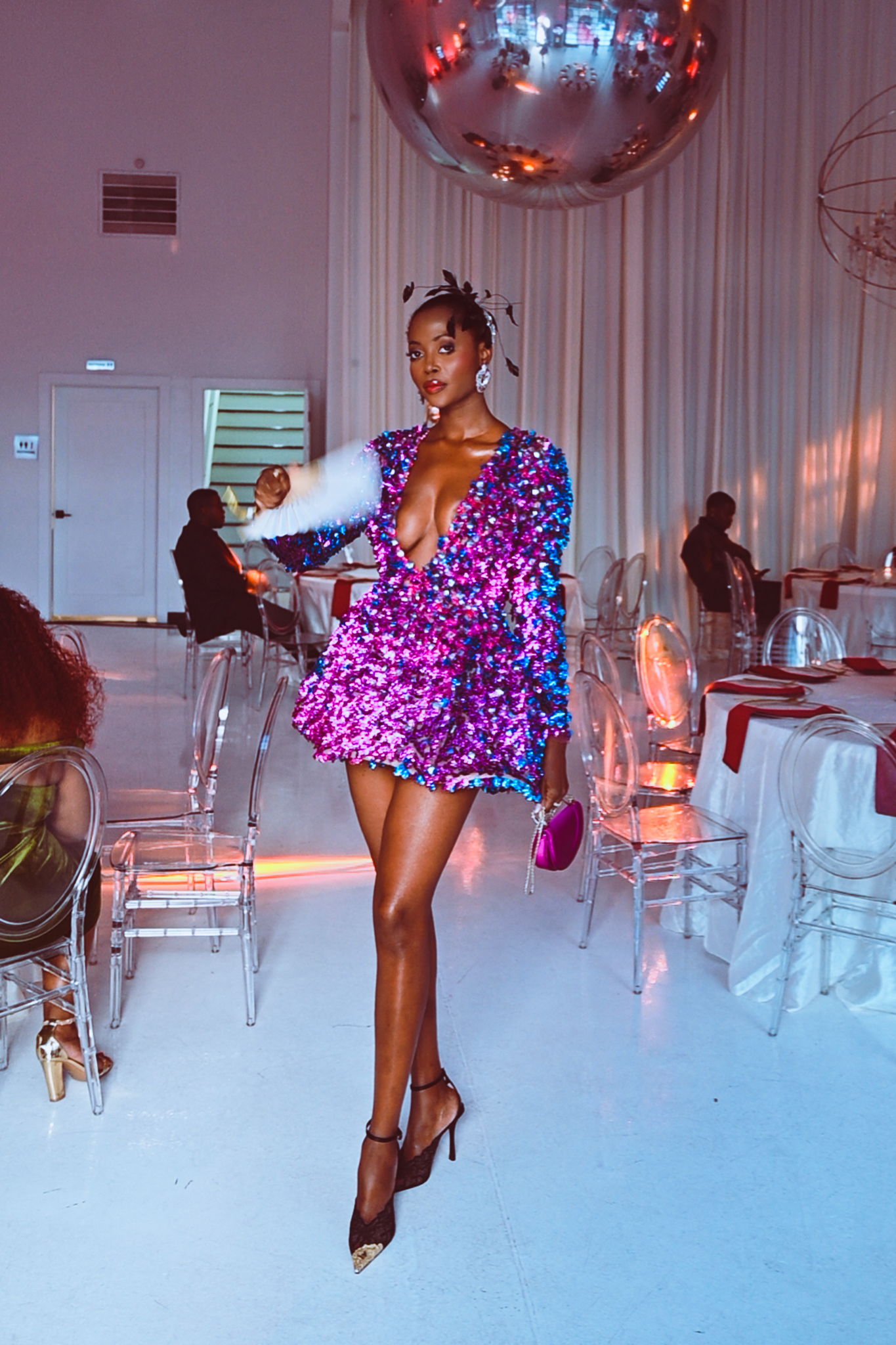 A model in a shimmering purple dress poses confidently in a stylish event space