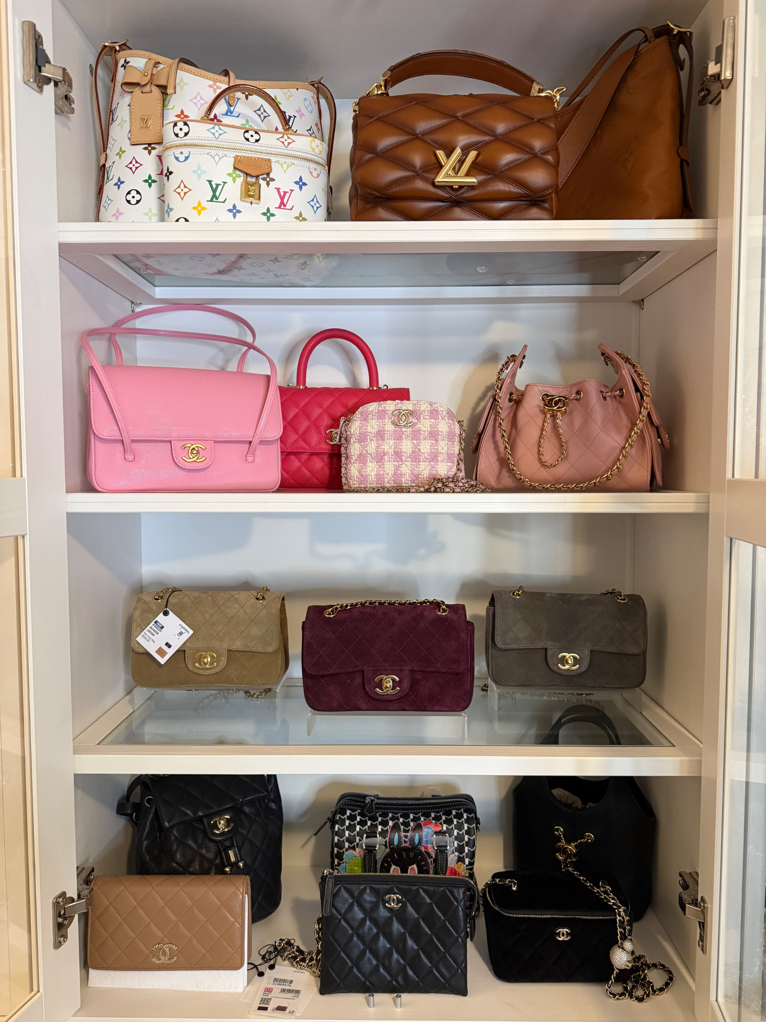 A display of various luxury handbags on shelves in a cabinet