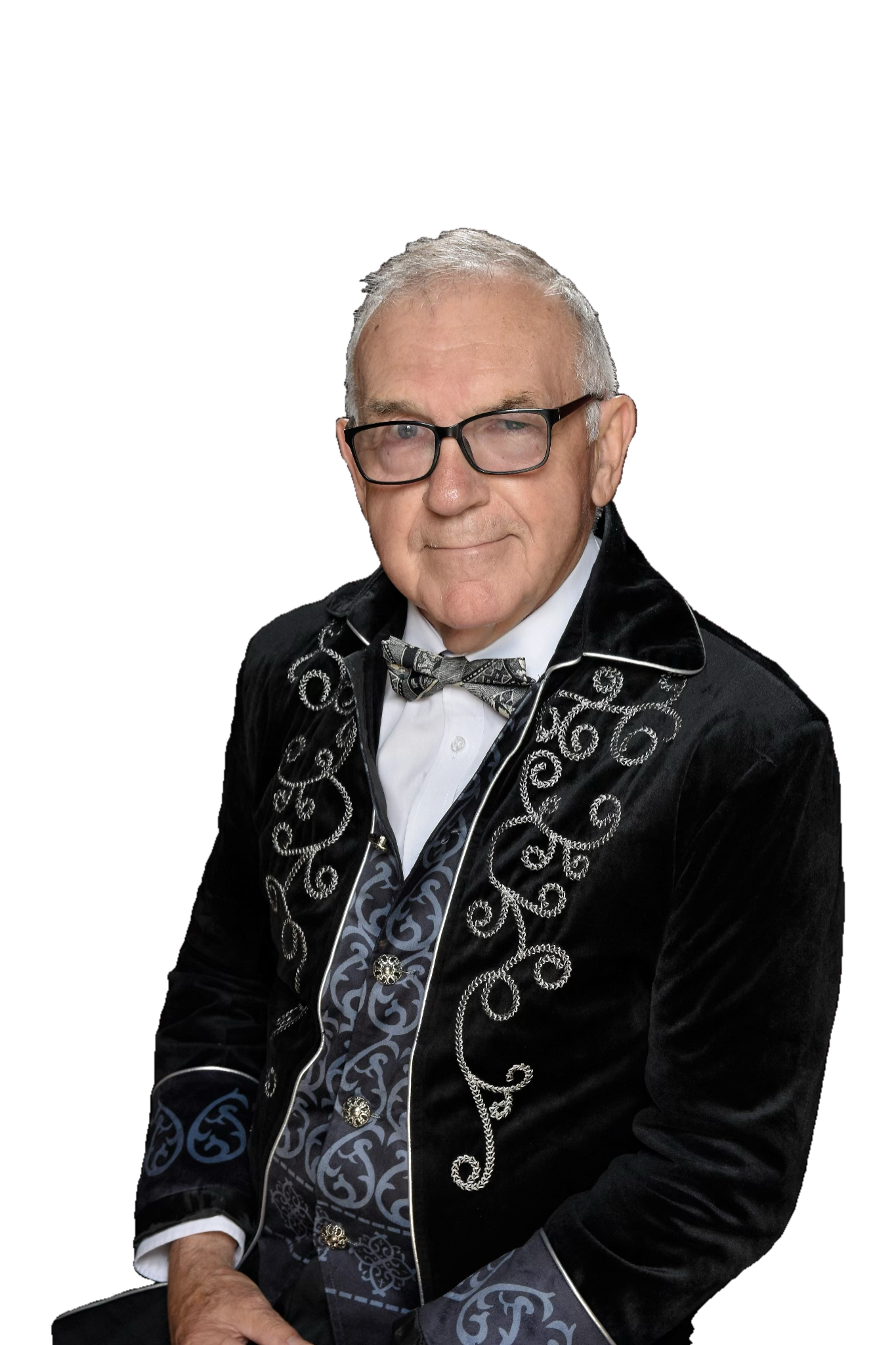 Elderly man in elegant black suit with intricate patterns and bow tie.