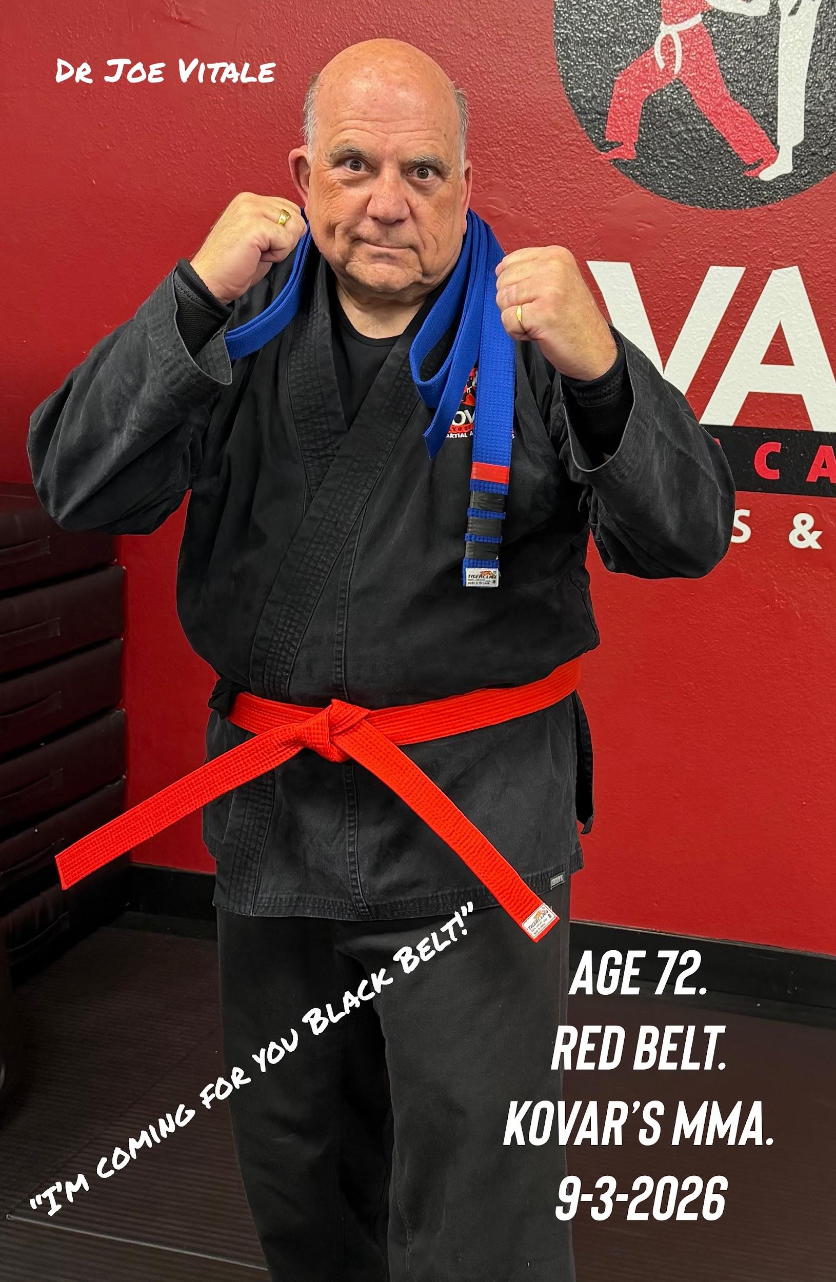 An older man in a black martial arts gi with a red belt poses confidently