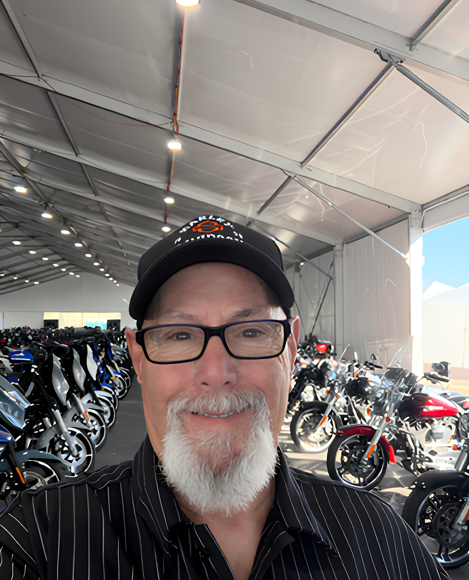 A smiling man in a cap stands in a motorcycle display area.