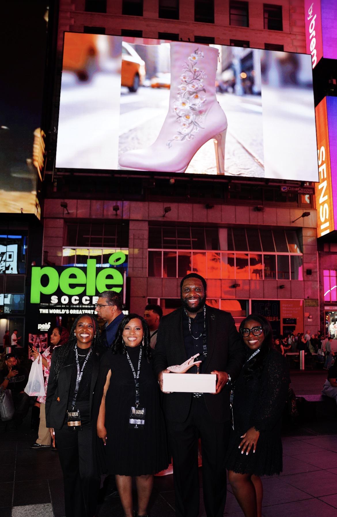 Four people pose in Times Square with a displayed high-heeled boot in the background