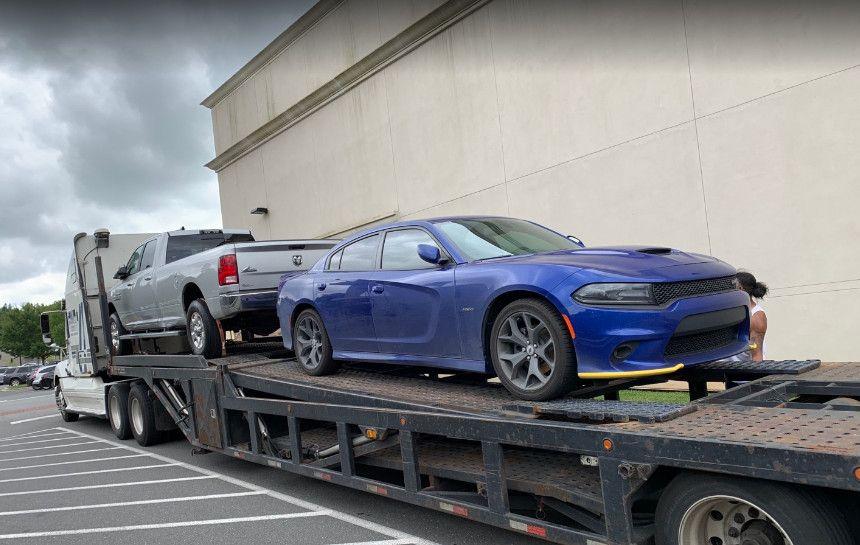 Blue Dodge Charger and a truck stacked on a car transport trailer.