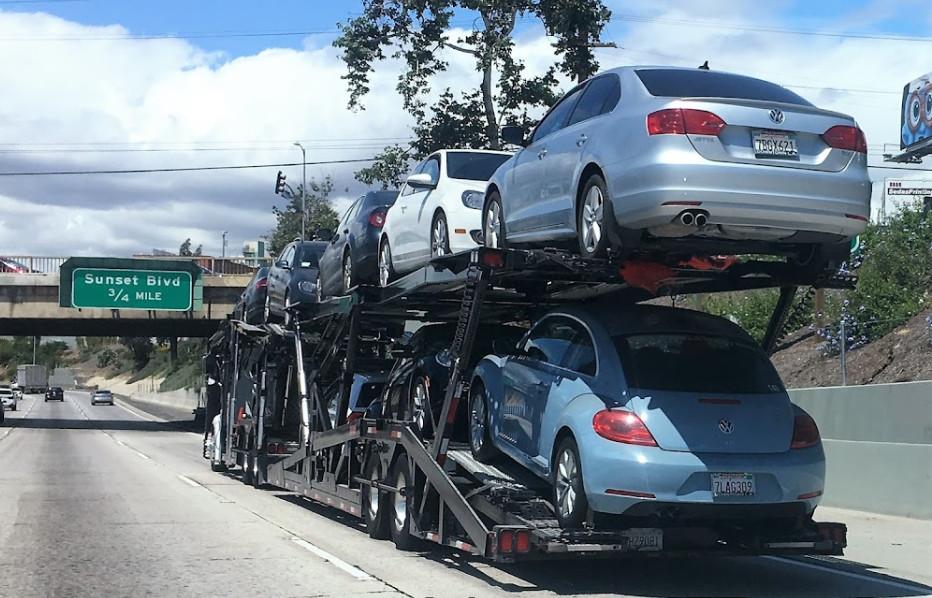 Car transport trailer on a highway carrying multiple vehicles stacked on top