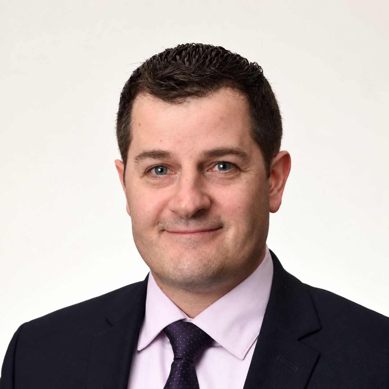 Professional man in a suit and tie with short dark hair and a slight smile