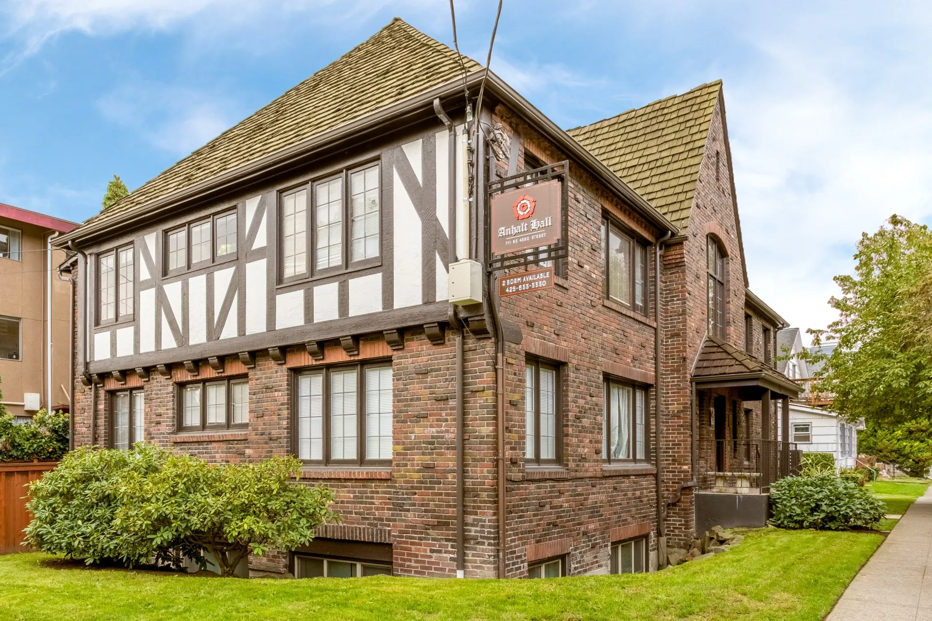 Historic brick building with Tudor-style accents and well-maintained greenery in front