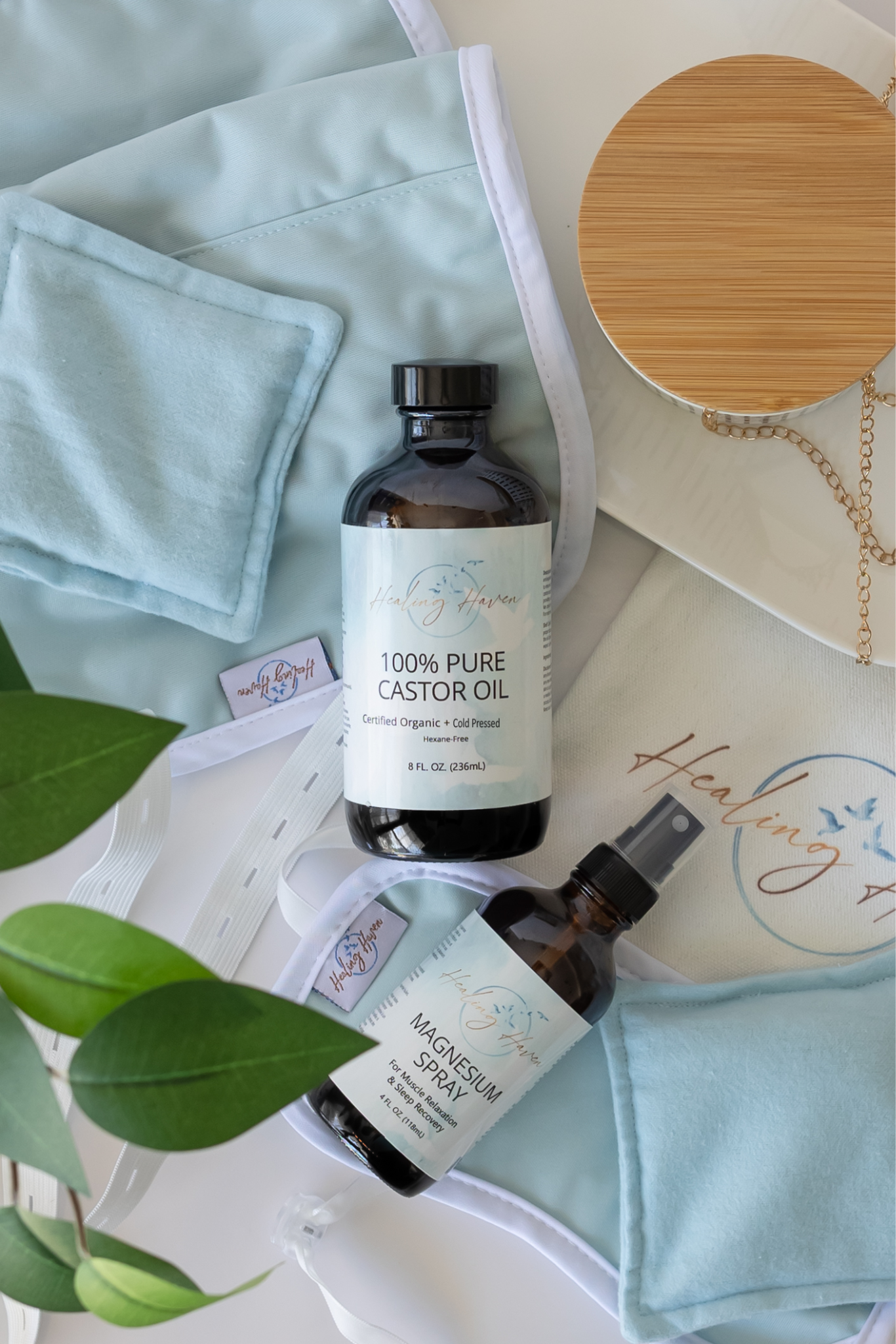 Bottles of castor oil and magnesium spray on a light blue background with greenery
