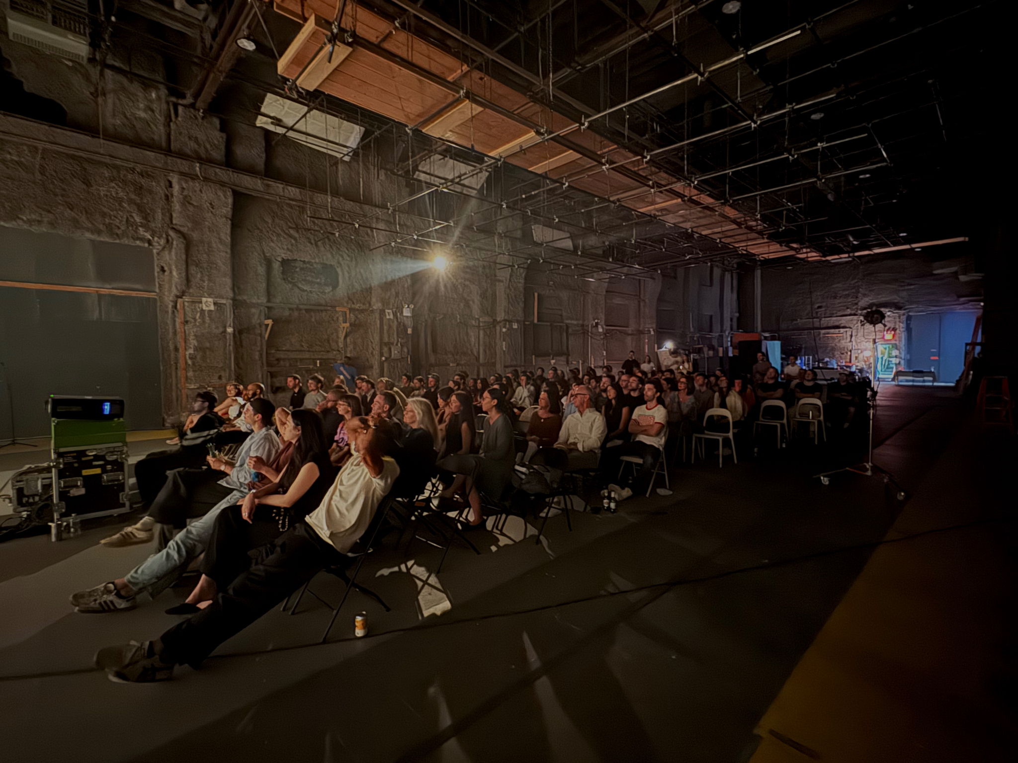 Audience seated in a dimly lit studio, watching a presentation on a screen