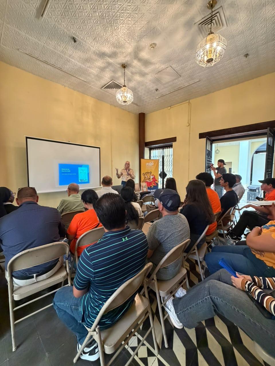 A presentation in a room with seated attendees listening to a speaker at the front