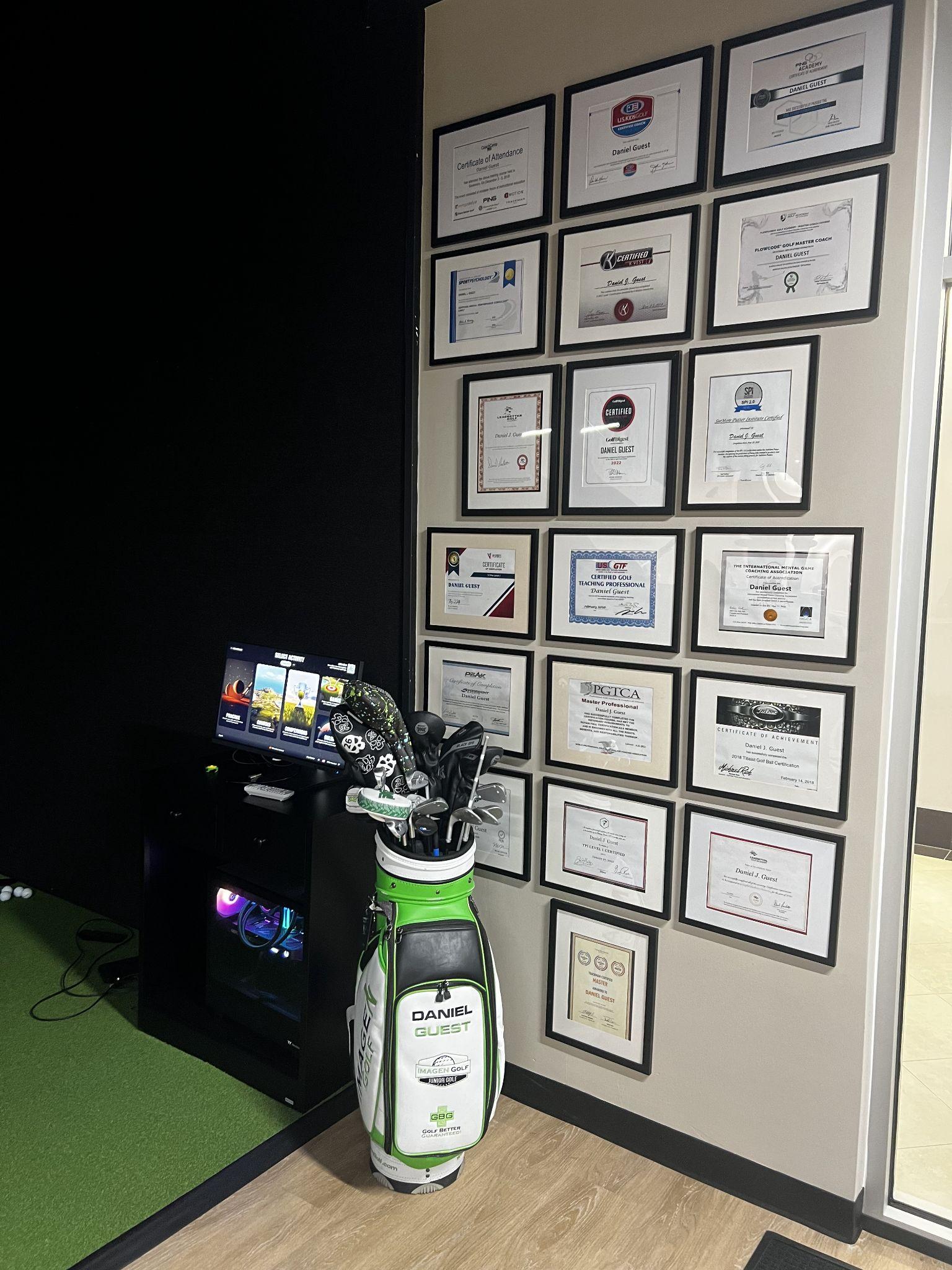 Golf clubs in a bag next to a wall of framed certificates and awards