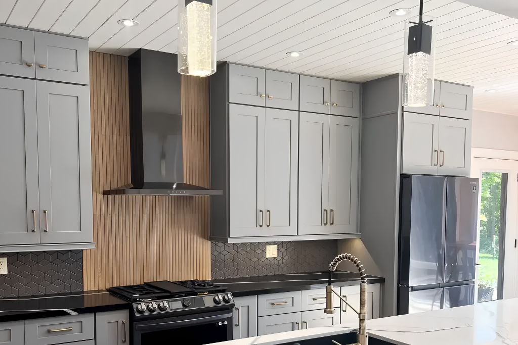Modern kitchen featuring gray cabinets, stainless steel appliances, and a stylish range hood