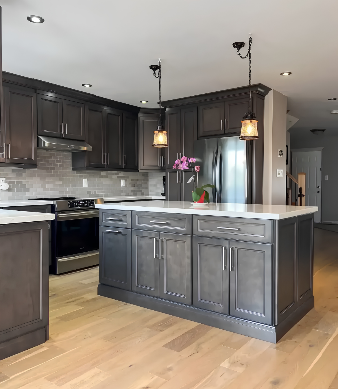 Modern kitchen with dark cabinetry, white countertops, and pendant lighting over the island