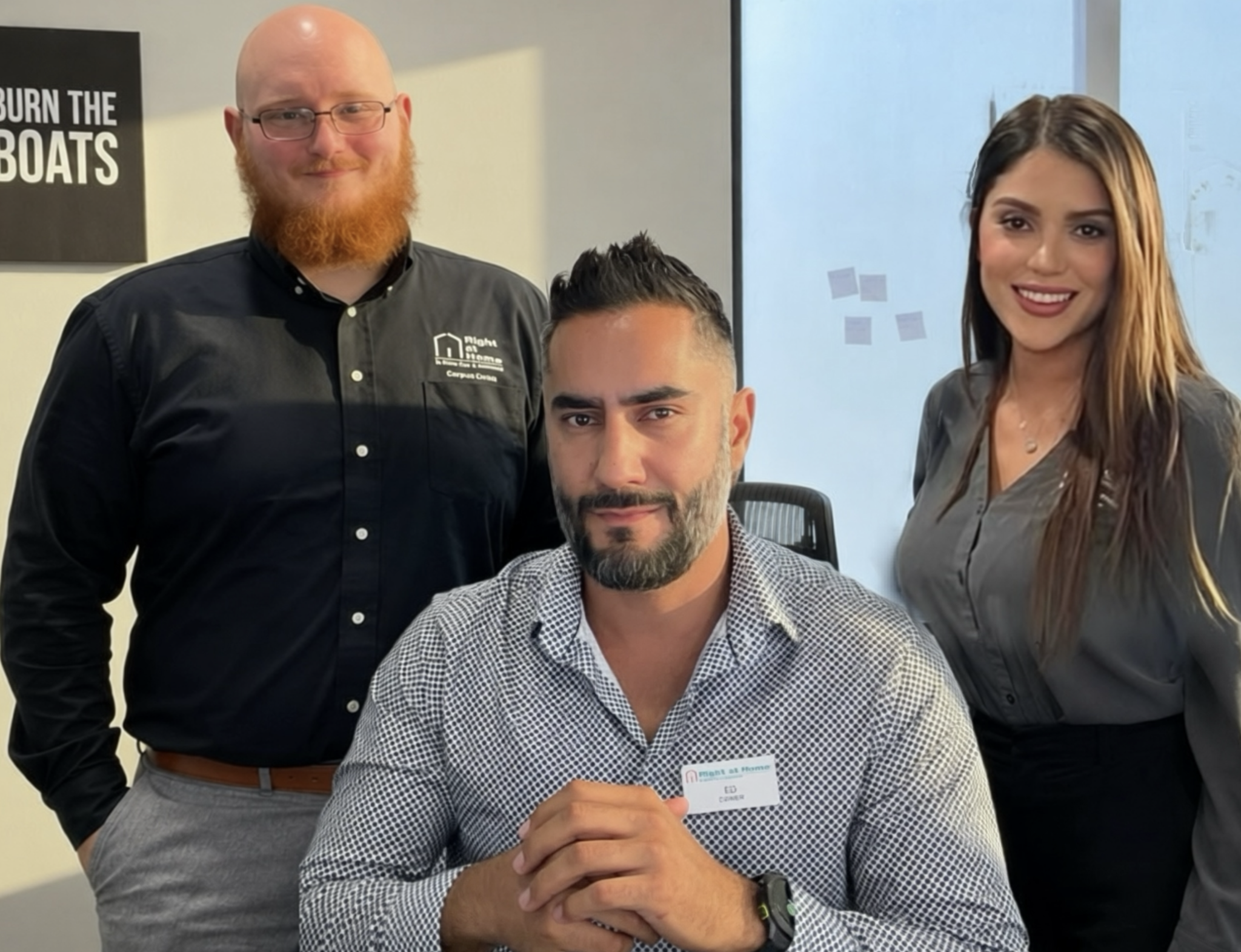 Three professionals posing in an office setting, two men and one woman.