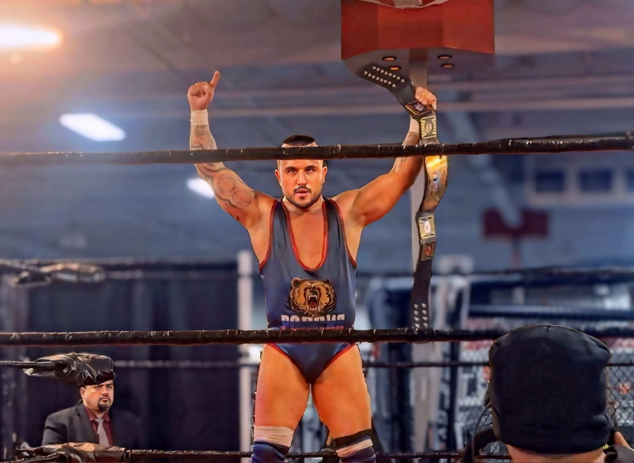 Wrestler celebrating victory in the ring, holding a championship belt aloft