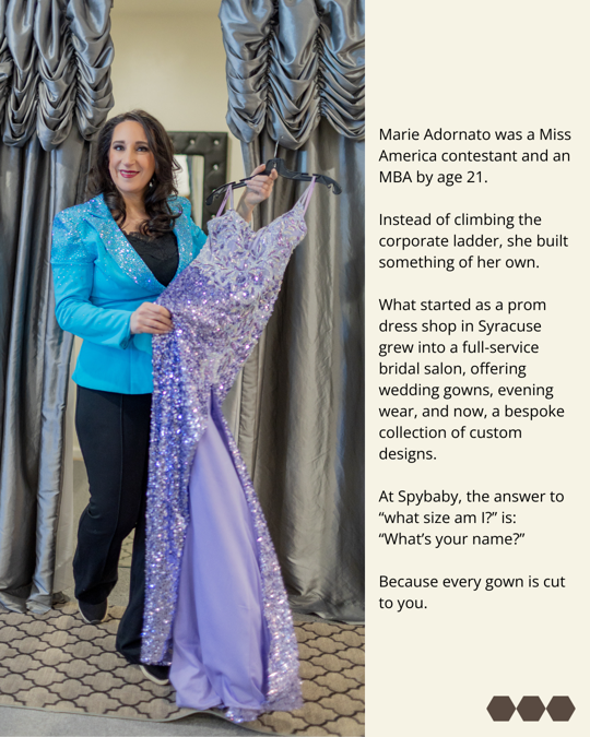 Woman in a blue jacket holds a purple evening gown in a boutique setting