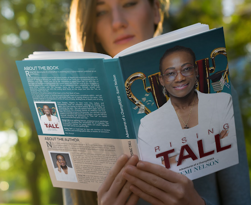 A woman reading a book titled "Rising Tall" in a park setting.