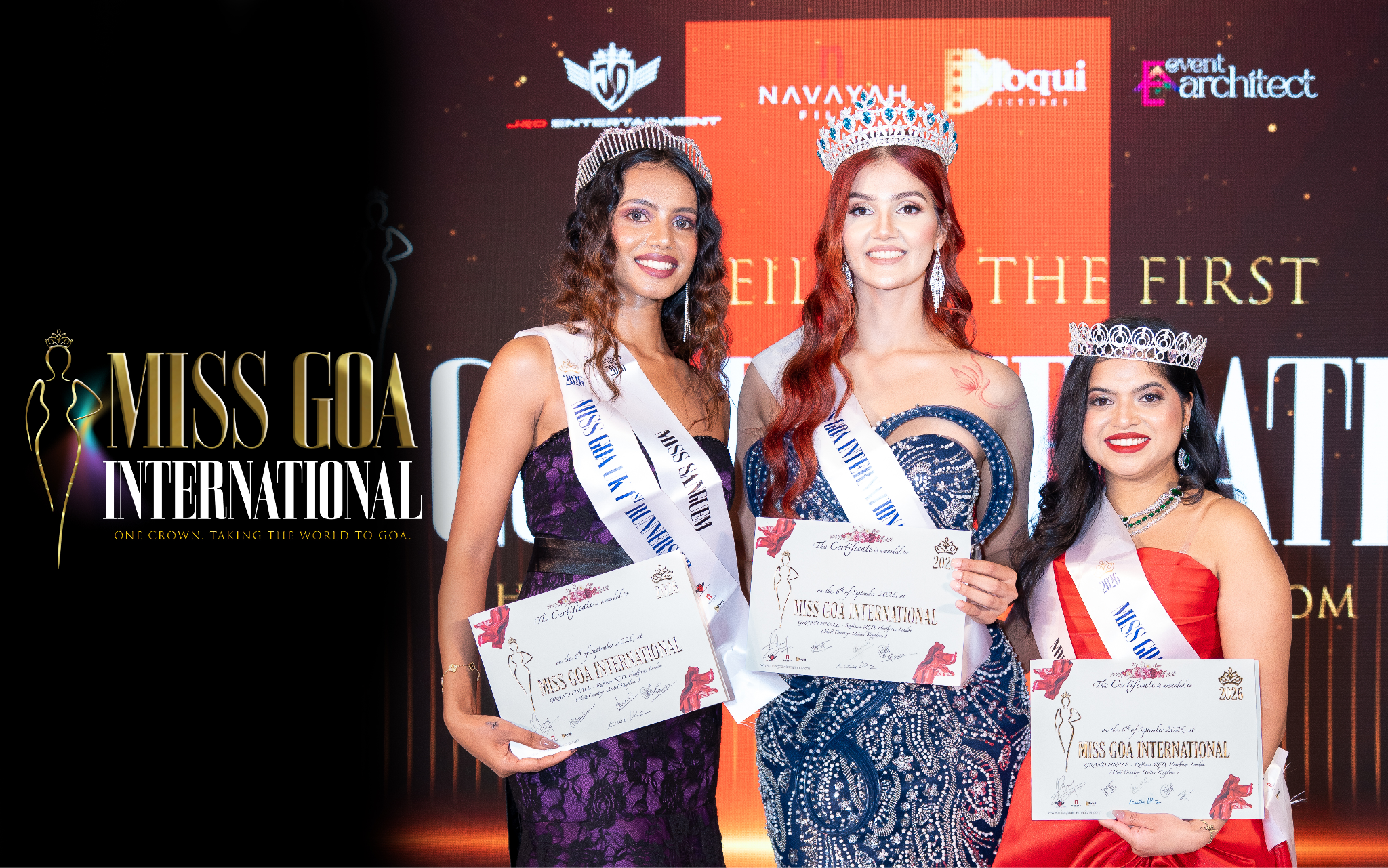 Three women holding awards, wearing sashes at Miss Goa International event background logo