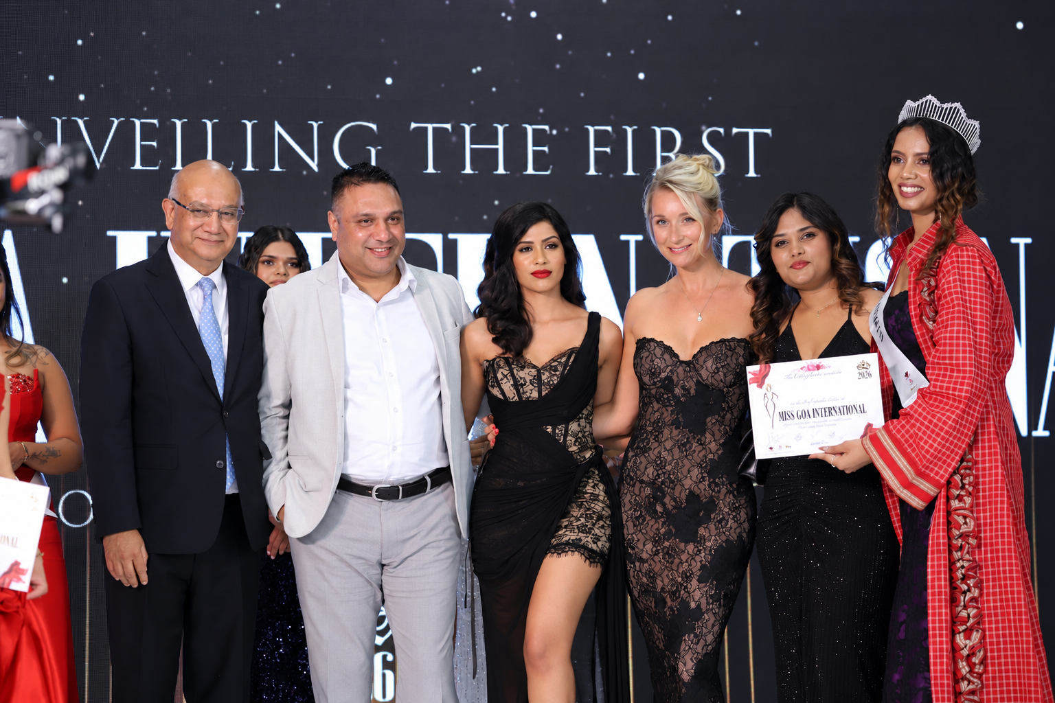 Group of people at an event, celebrating and holding certificates on stage.