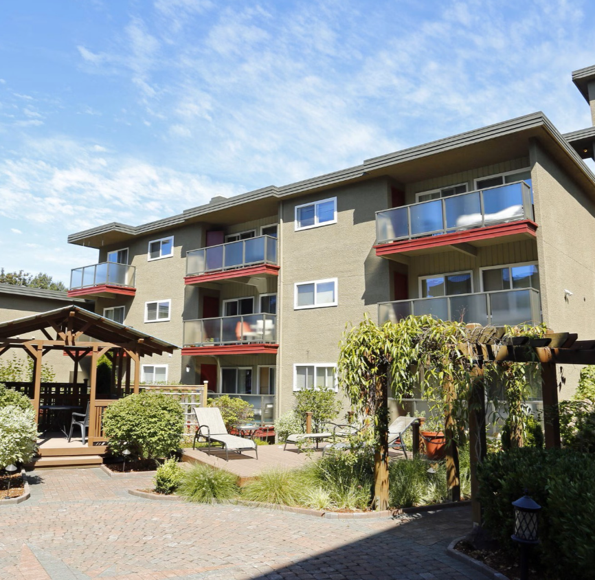 Apartment complex with a landscaped courtyard and a gazebo under a blue sky