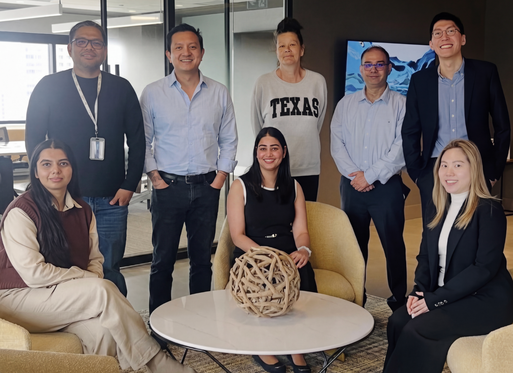 Group of eight diverse professionals posing together in a modern office setting