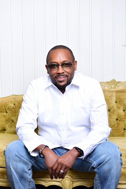 Man sitting on a vintage yellow couch, wearing a white shirt and jeans