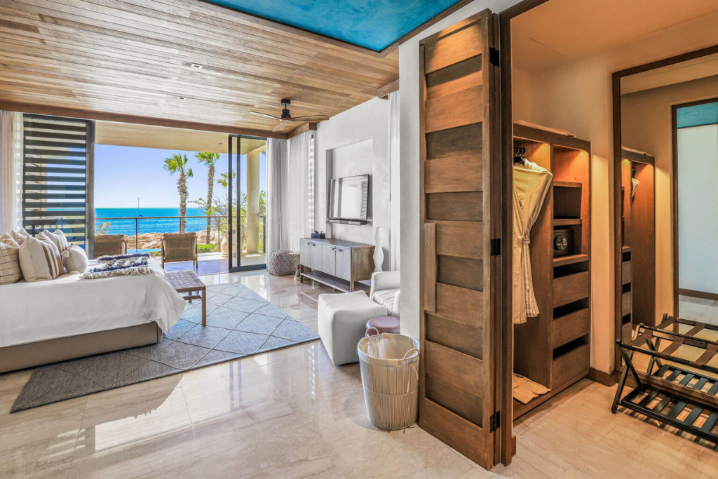 Bright hotel room with ocean view, featuring modern decor and open wardrobe.