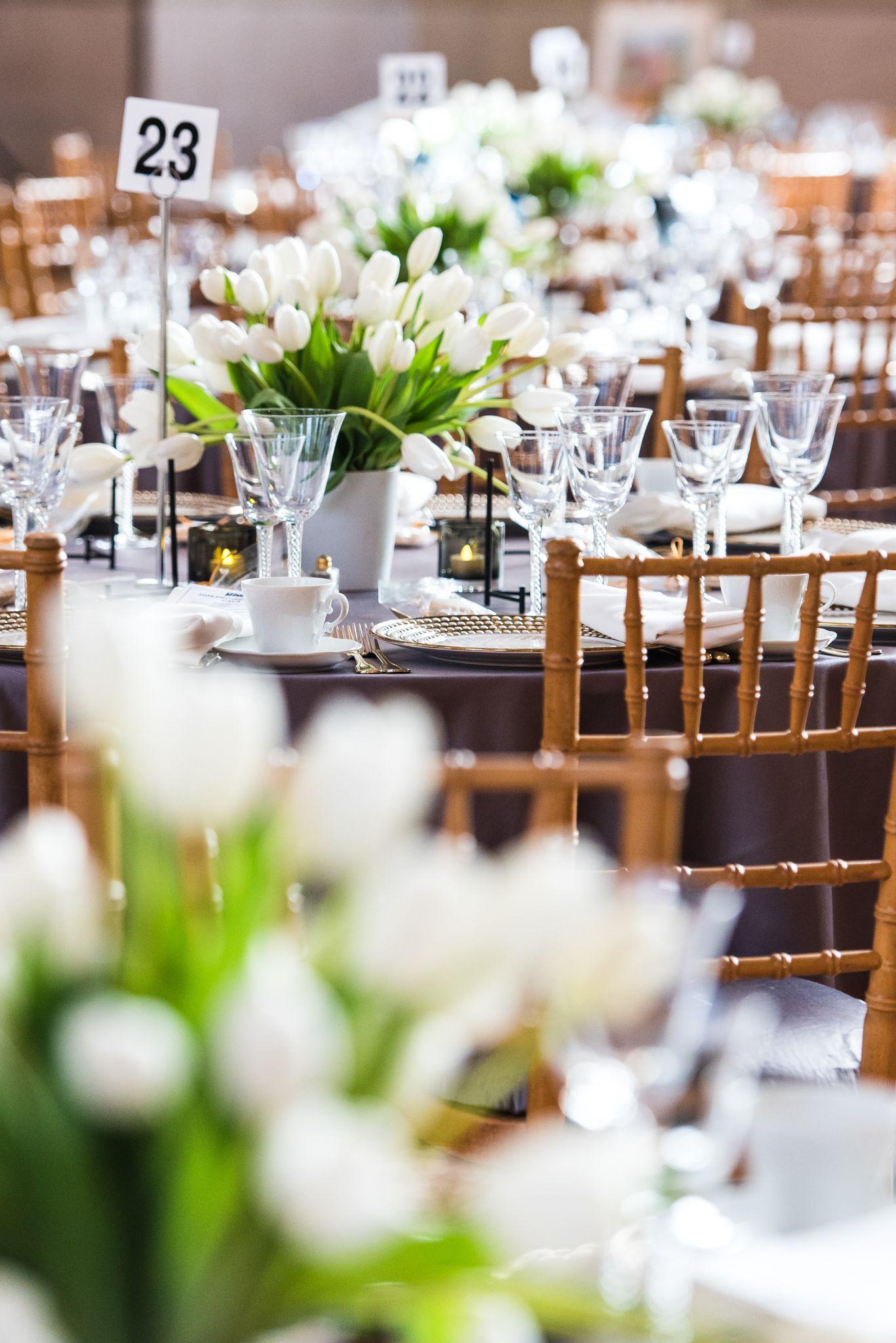 Elegant dining setup with tulip centerpieces and neatly arranged glassware on tables