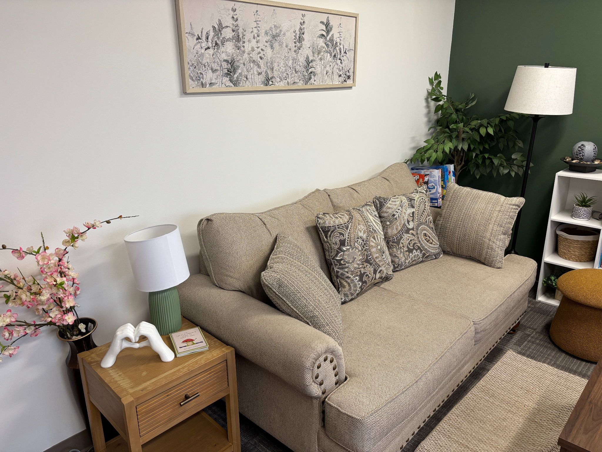 Cozy living room scene with a sofa, lamp, plant, and decorative table.
