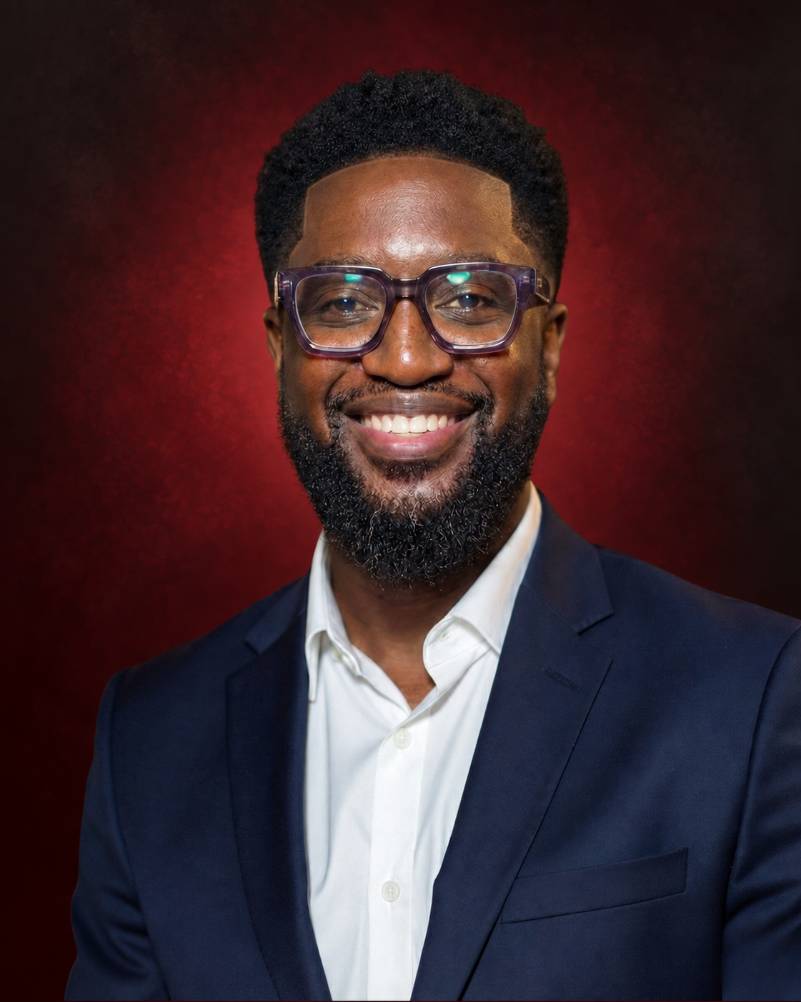Smiling man in a suit with glasses against a red background