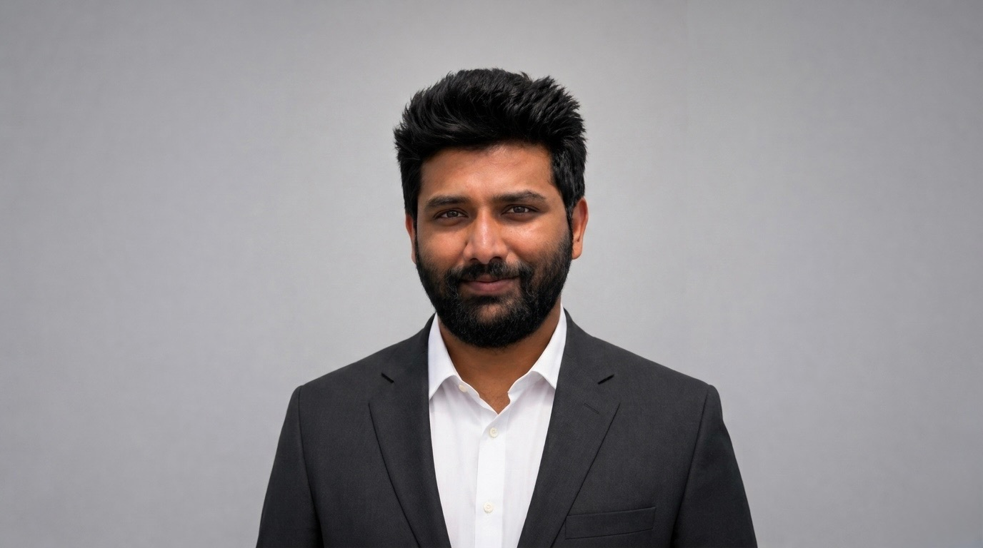 Man in a suit with a beard against a gray background.