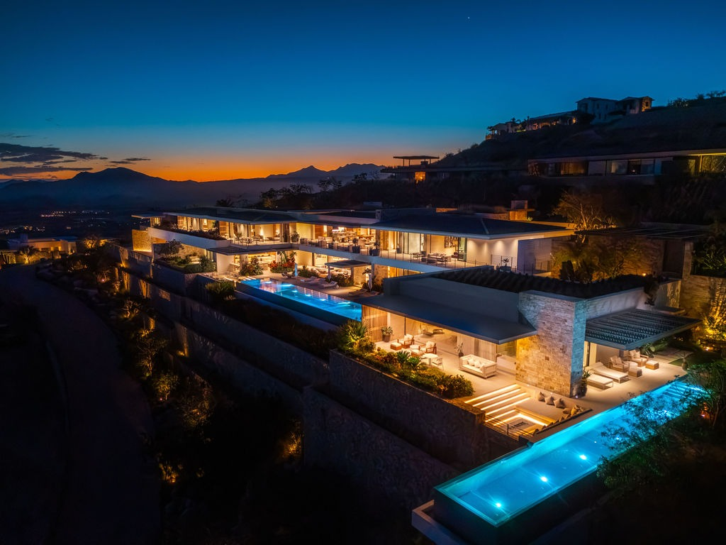 Luxury hillside villa illuminated at twilight with pools and panoramic views