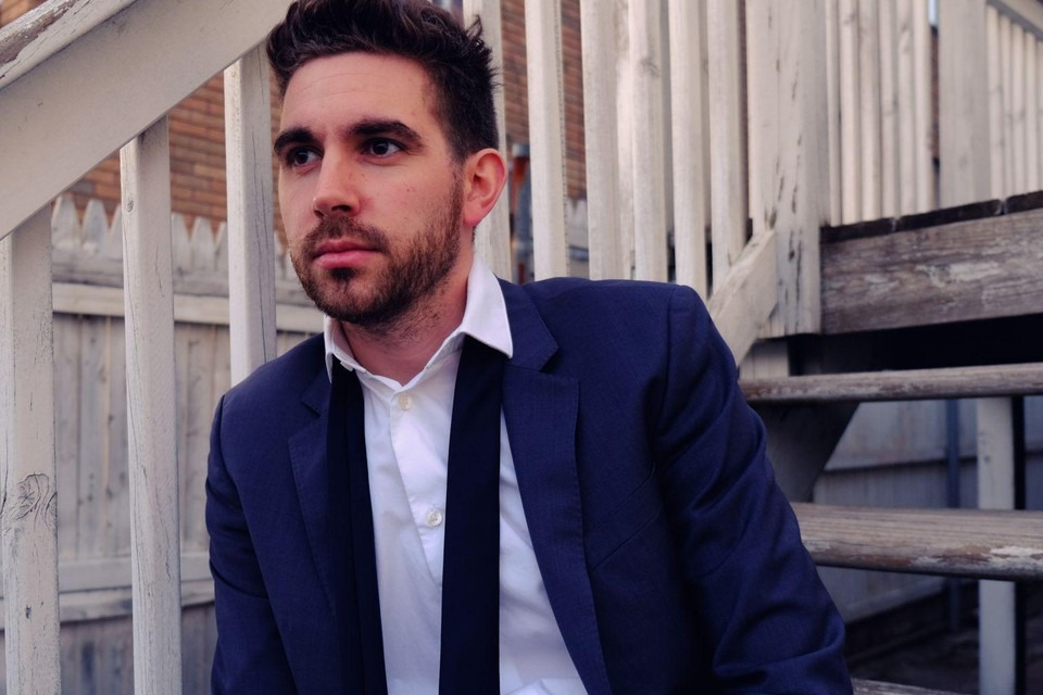 Man in a suit sitting on stairs, looking contemplative with disheveled tie