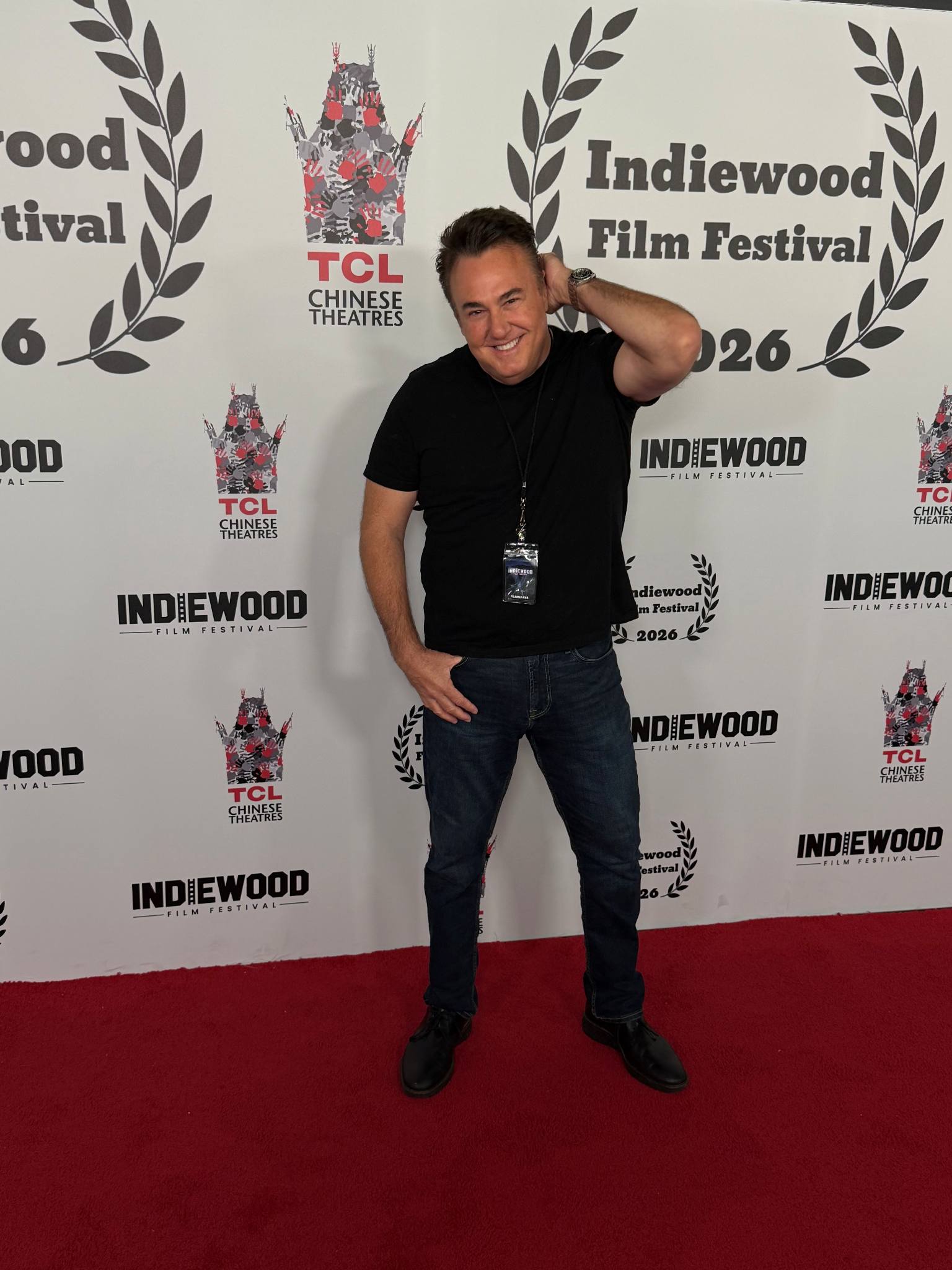 Person posing on a red carpet at the Indiewood Film Festival backdrop