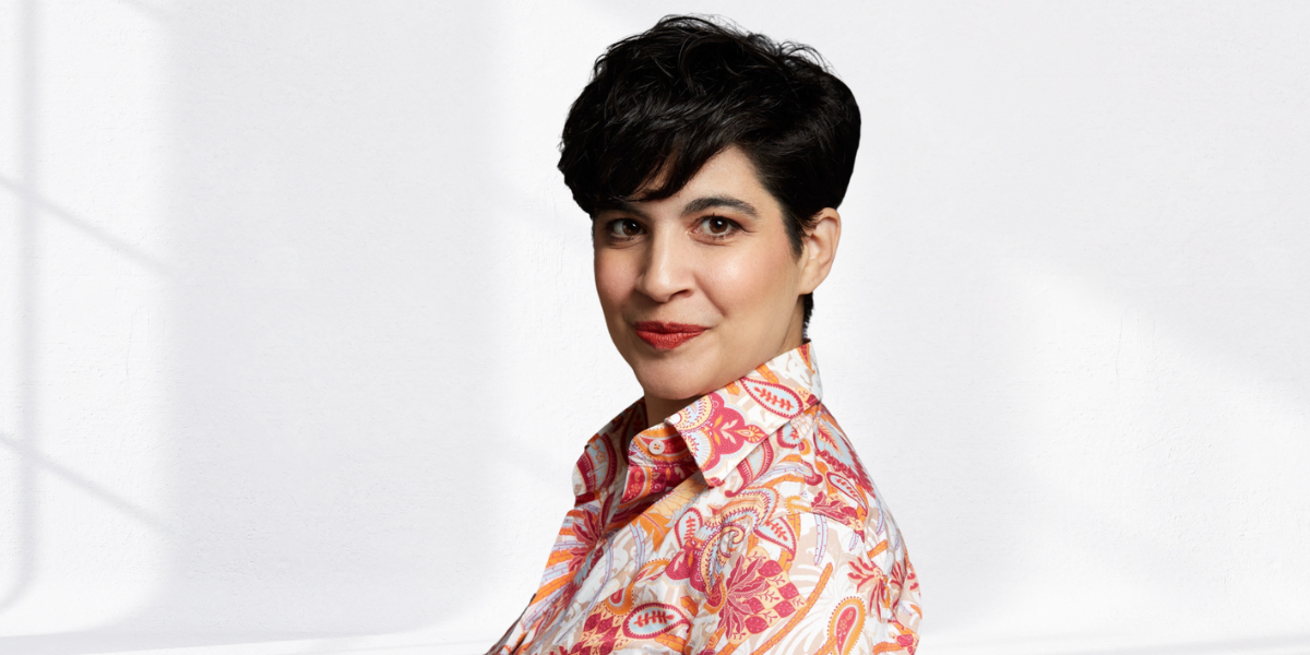 Portrait of a woman with short dark hair in a colorful shirt against a light background